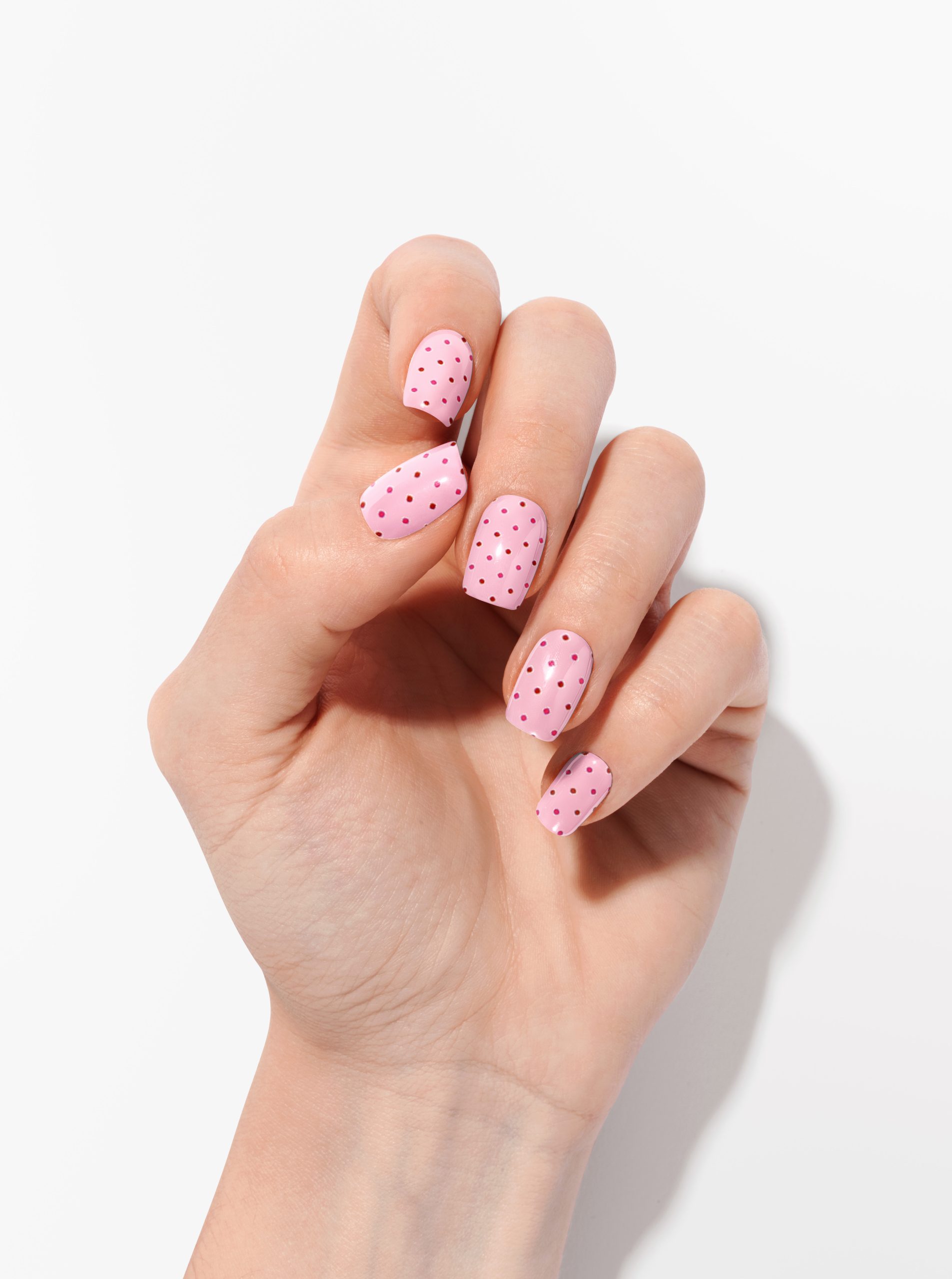 Manucure avec motifs à pois roses sur fond rose pâle