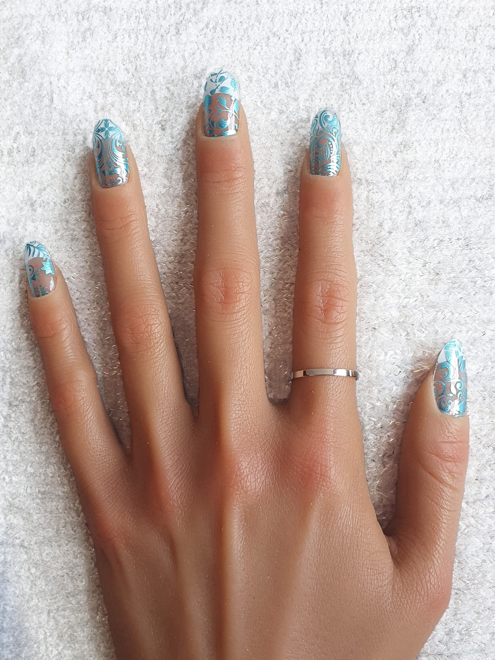 Manucure aux motifs floraux et tourbillonnants en nails stickers bleus.