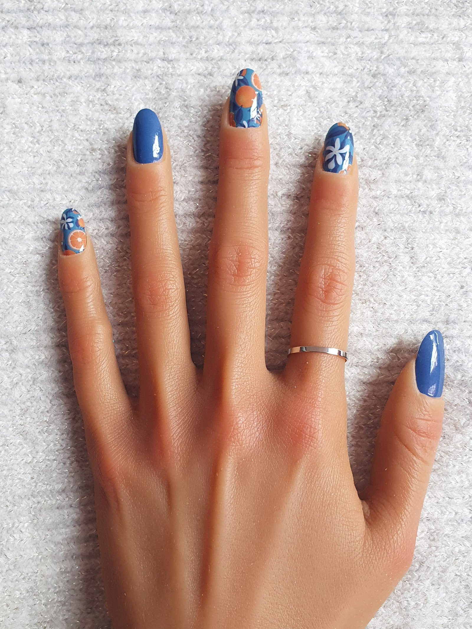 Manucure colorée avec des designs d'ongles adhésifs bleus avec des oranges.