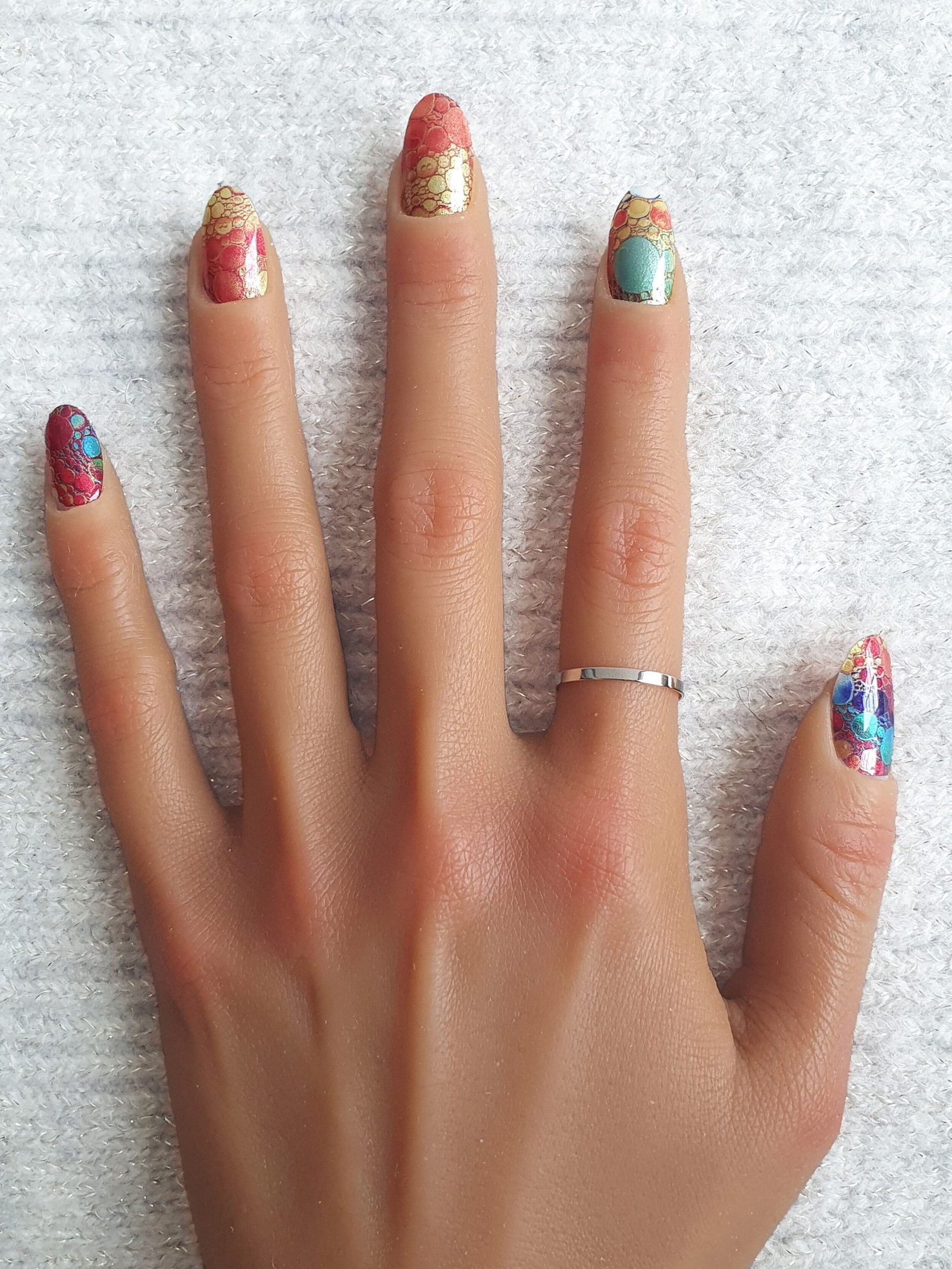 Ongles décorés avec des stickers nail art vifs, aux motifs colorés et métallique.