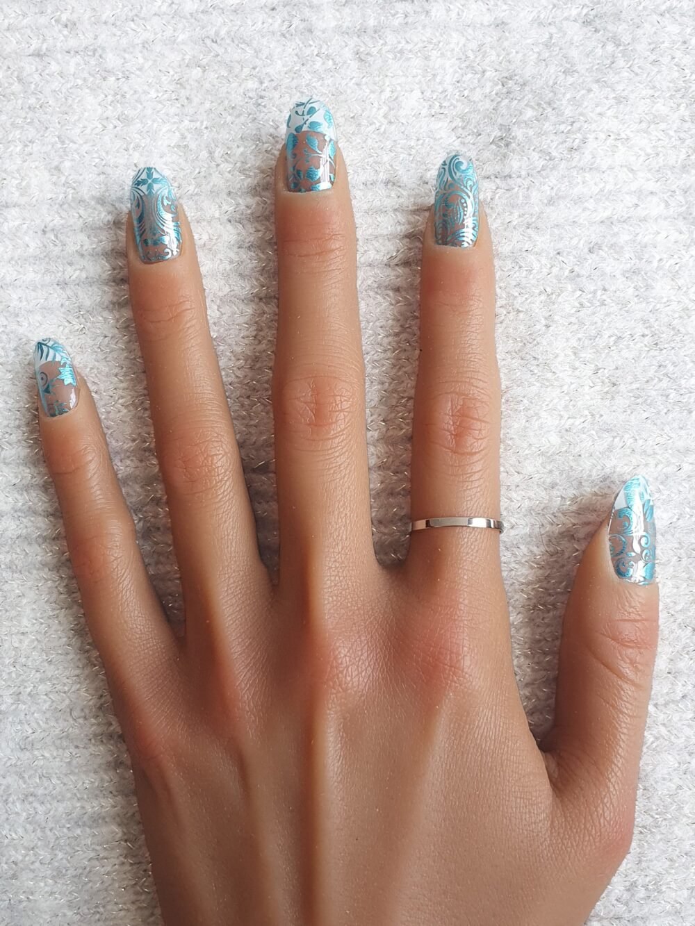 Manucure aux motifs floraux et tourbillonnants en nails stickers bleus.